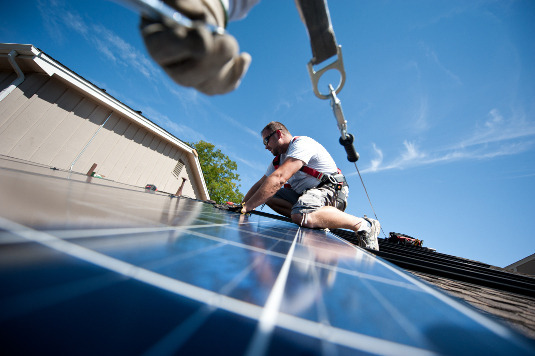 September 10, 2012- REC Solar employees Mario Richard (left hand visible) and Brian Webster, right,  install PV modules on a Englewood, CO home participating in the Solar Benefits Colorado program. (Photo by Dennis Schroeder / NREL)