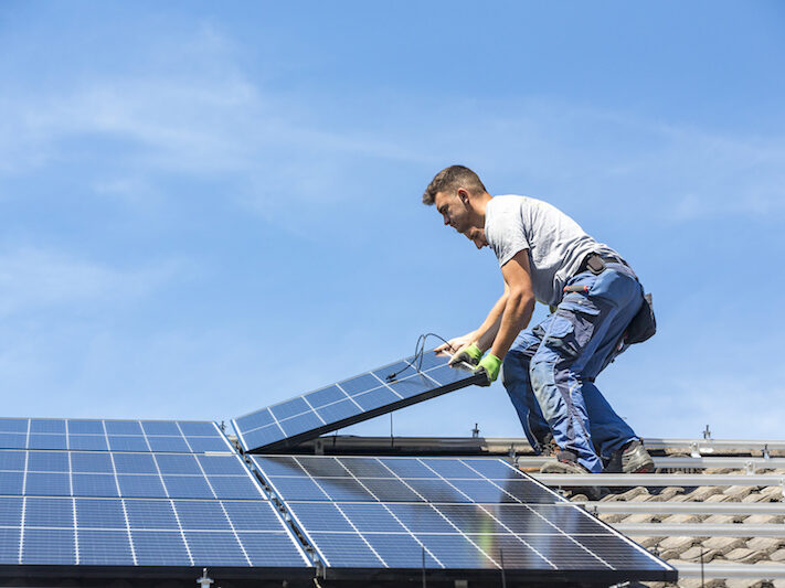 Installing solar photovoltaic panel system. Solar panel technician installing solar panels on roof. Alternative energy ecological concept.