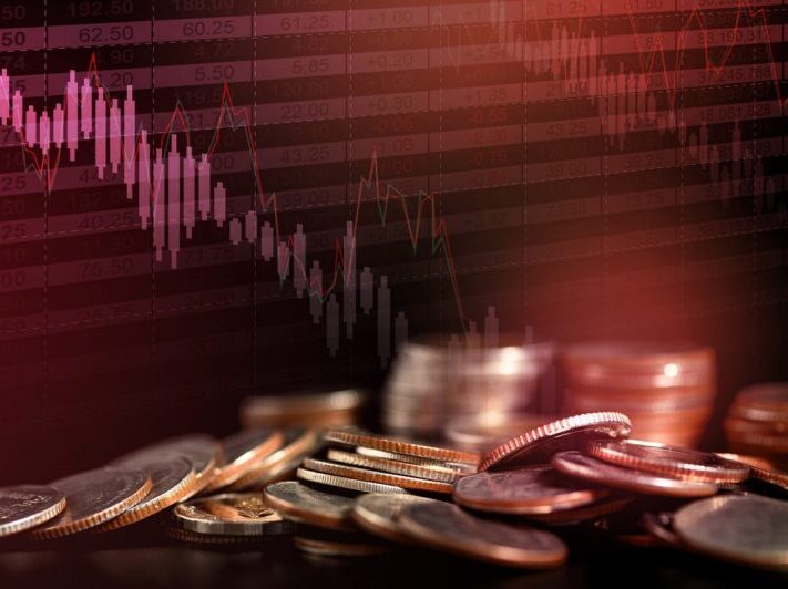 Pile of coins on black background with red light, dropped financial graph and stock table. Double exposure with copy space. Money concept.