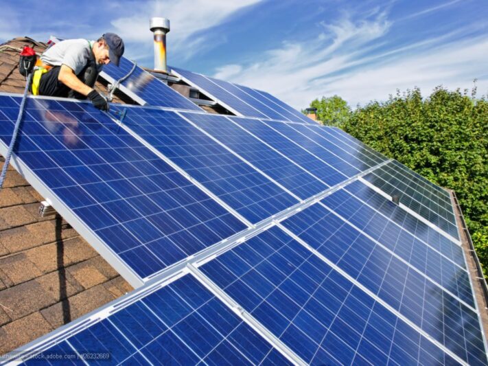Man-installing-alternative-energy-photovoltaic-solar-panels-on-roof