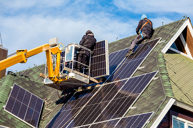 Workers installing solar panels on private home hexagonal roof f